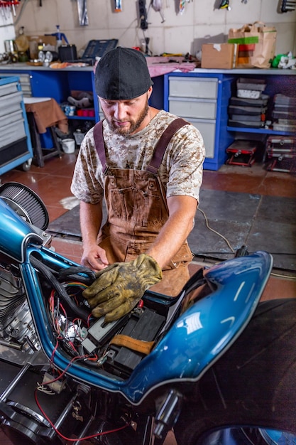 Ritratto di vista laterale dell'uomo che lavora in garage riparazione moto e personalizzazione