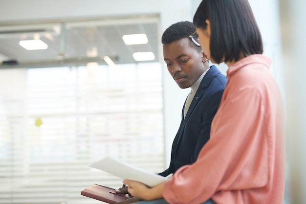 Ritratto di vista laterale dell'uomo d'affari africano di successo che parla al collega femminile