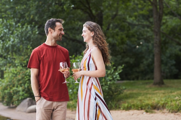 Ritratto di vista laterale di coppia felice che tiene bicchieri di vino mentre si gode un appuntamento romantico all'aperto copia s...