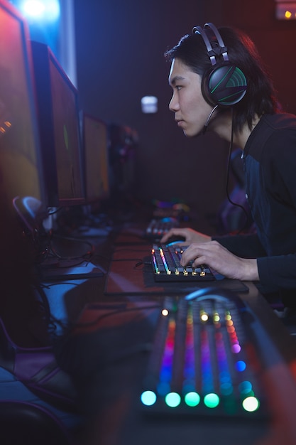 Ritratto di vista laterale verticale di giovane uomo asiatico che utilizza computer in studio di cyber hacking, copia dello spazio