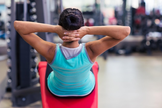 Ritratto di vista posteriore di un allenamento di donna fitness sulla macchina esercizi in palestra