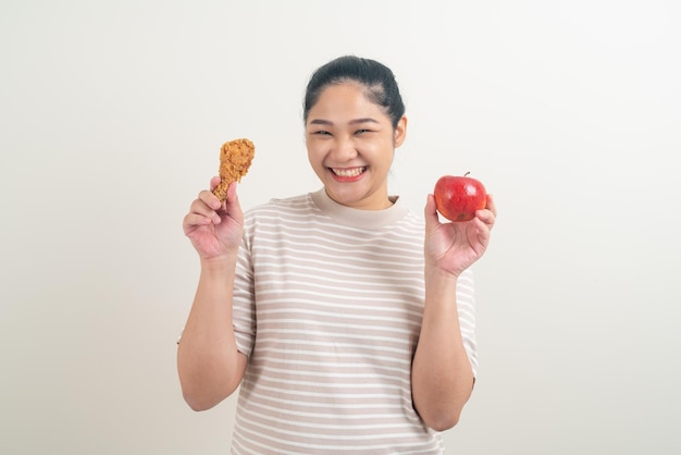 ritratto donna asiatica con pollo fritto e mela a portata di mano per la scelta