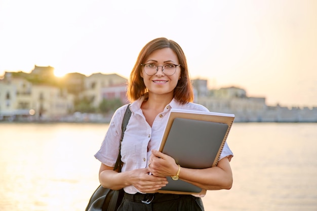 Ritratto donna di affari di mezza età con il computer portatile in mano guardando a porte chiuse