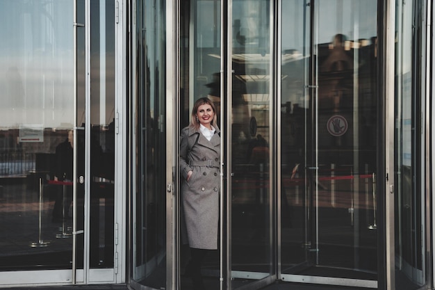 Ritratto elegante donna d'affari all'aperto sullo sfondo del quartiere degli affari. Donna d'affari in abiti casual nella città finanziaria. Bella donna sorridente in abiti di stile in costruzione. Copia spazio