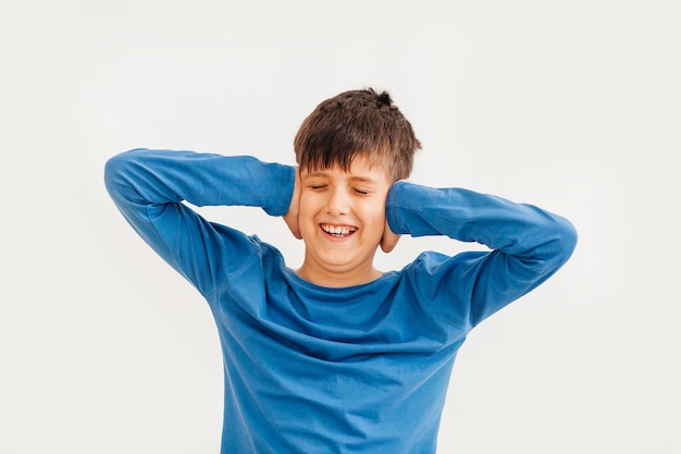 Ritratto emotivo a mezzo busto di ragazzo adolescente caucasico che indossa t-shirt blu. Adolescente sorpreso che guarda l'obbiettivo. Bel bambino felice, isolato su sfondo bianco.