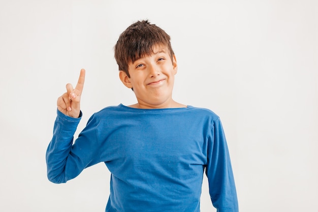 Ritratto emotivo a mezzo busto di ragazzo adolescente caucasico che indossa t-shirt blu. Adolescente sorpreso che guarda l'obbiettivo. Bel bambino felice, isolato su sfondo bianco.