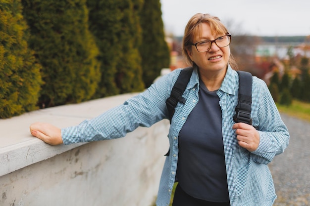 Ritratto esterno di felice pensionata europea con zaino che si gode la splendida natura mentre cammina nordico Persone anziane stile di vita attivo e concetto di salute