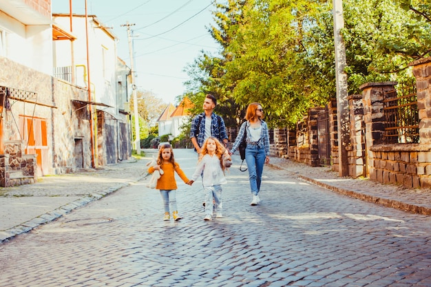 Ritratto estivo di famiglia di giovani genitori e figlie che camminano insieme durante il loro viaggio in tutto il paese. Turisti che passeggiano per la città vecchia di Uzhhorod, Ucraina