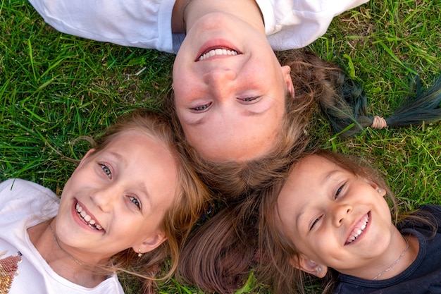 Ritratto estivo di tre sorelle. Le ragazze carine sono sdraiate sull'erba e sorridenti. bambini sorridenti all'aperto. Concetto di estate.