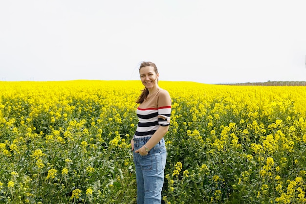 Ritratto estivo di una donna felice in piedi in un campo giallo