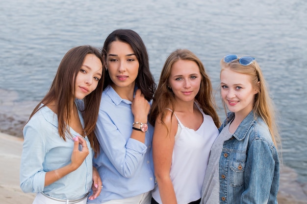 Ritratto felice di quattro amiche che guardano amichevoli alla macchina fotografica, sorridono, felici. persone, stile di vita, concetto di amicizia