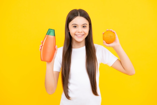 Ritratto felice di una ragazza adolescente con shampoo, balsami e gel doccia Cura dei capelli lunghi dell'adolescente Presentazione del flacone di shampoo per prodotti cosmetici Ragazza sorridente