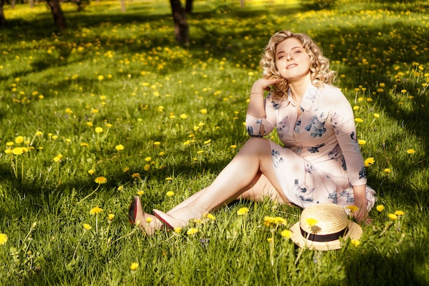 Ritratto femminile all'aperto. Donna con un cappello di paglia in un campo di fiori. Estate in campagna