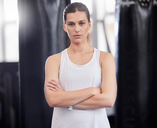 Ritratto fitness e boxe con una donna sportiva in una palestra in piedi con le braccia incrociate sentirsi seri o fiduciosi Allenamento fisico e concentrazione con un pugile o atleta femminile in piedi in uno studio di salute