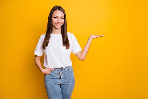 Ritratto fotografico di una ragazza che tiene in mano uno spazio vuoto isolato su uno sfondo di colore giallo brillante