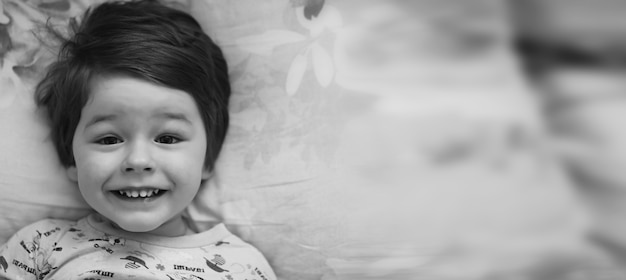 Ritratto fotografico in bianco e nero di un bambino sdraiato sul cuscino