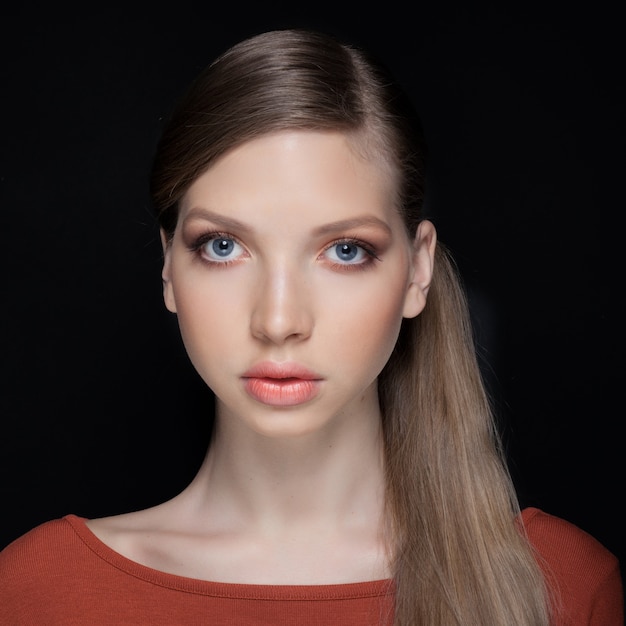 Ritratto frontale di bella giovane donna con trucco naturale luminoso e capelli stretti nella coda. Bella ragazza con bellissimi occhi, guardando la fotocamera.