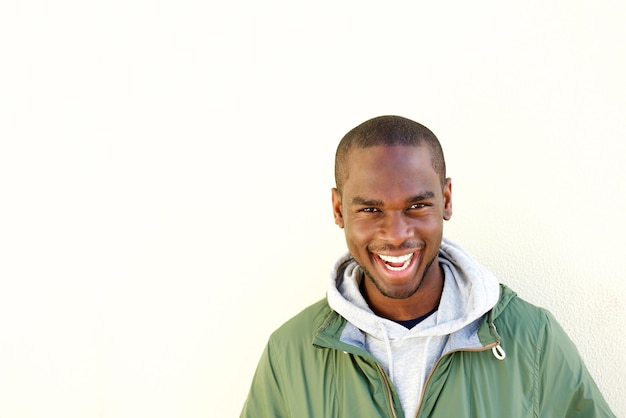 Ritratto frontale di giovane uomo afroamericano felice in posa vicino al muro