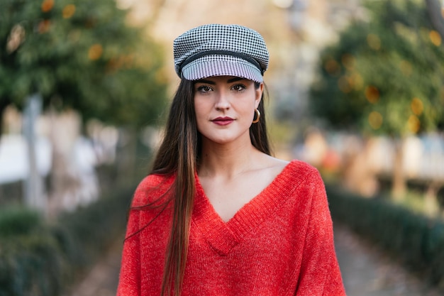 Ritratto frontale di una bella donna in maglione rosso e berretto scozzese bianco e nero