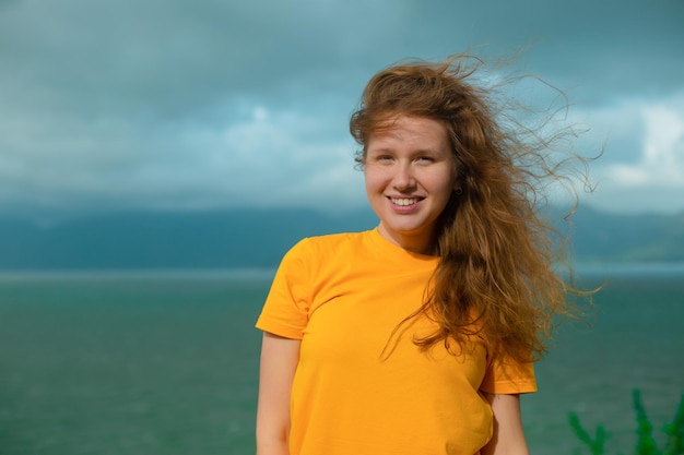 Ritratto giovane bella ragazza viaggia escursionismo a piedi con uno zaino nella vista sulle montagne sulle isole sorridendo il vento tra i capelli maltempo guardando il paesaggio della baia del mare