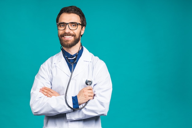 Ritratto giovane medico barbuto con lo stetoscopio sul collo in cappotto medico in piedi su sfondo blu isolato.