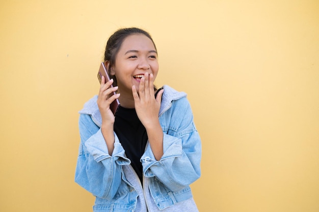 Ritratto giovane ragazza indossare giacca jean e utilizzare cellulare su sfondo marrone.