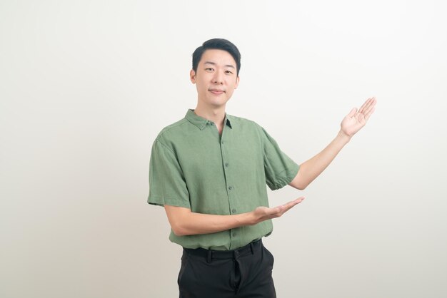 ritratto giovane uomo asiatico con la mano che punta o presenta su sfondo bianco