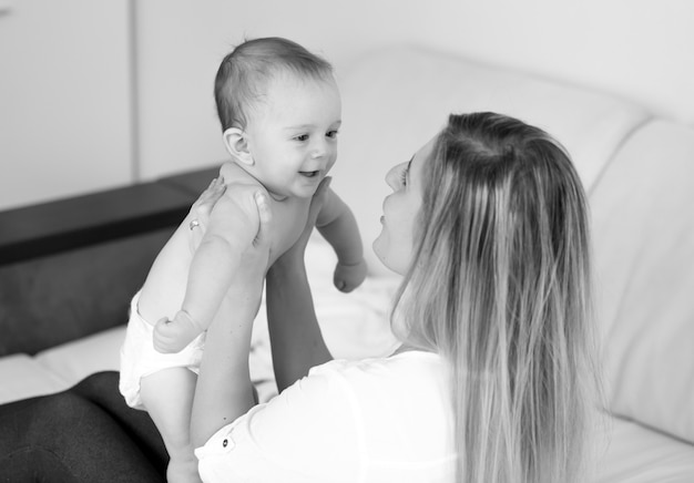 Ritratto in bianco e nero della madre felice che tiene il bambino sulle mani