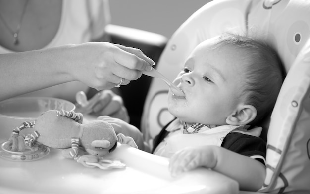 Ritratto in bianco e nero di giovane madre sorridente che allatta il suo bambino