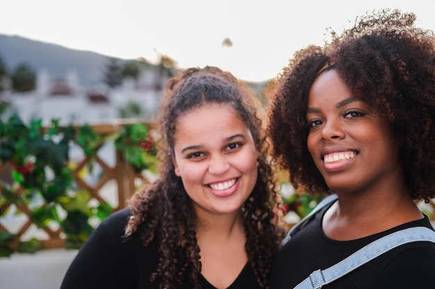 Ritratto in primo piano di due giovani con i capelli ricci e sorridenti sulla terrazza della loro casa Sorriso del ritratto di stile di vita di concetto