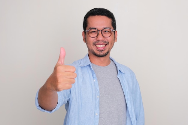 Ritratto in primo piano di un uomo asiatico sorridente con il pollice in alto