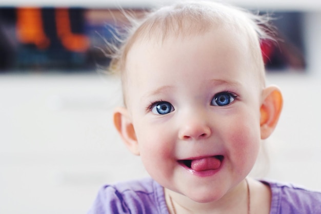Ritratto in primo piano di una bambina che tira fuori la lingua a casa
