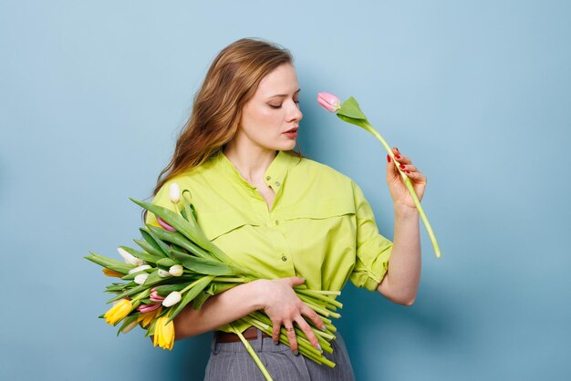 ritratto in primo piano di una donna con un bouquet di fiori di tulipano su uno sfondo blu pulito congratulazioni concetto