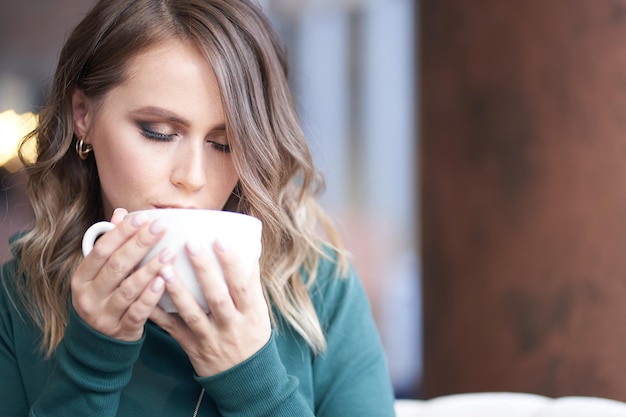 Ritratto in primo piano di una donna con una manicure che tiene una tazza di caffè una ragazza che beve caffè