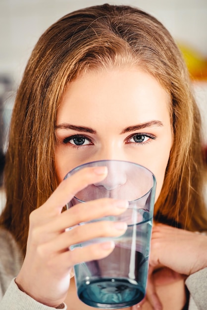 Ritratto in primo piano di una giovane donna che beve acqua da un bicchiere