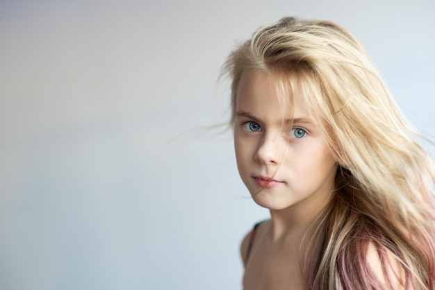 Ritratto in primo piano di una ragazza dai capelli biondi su uno sfondo bianco