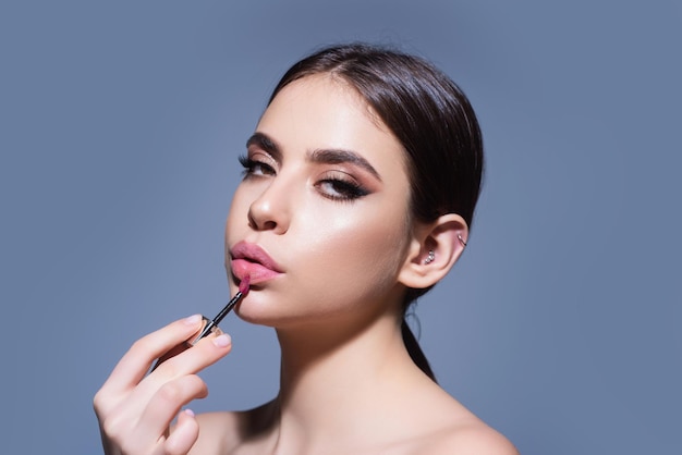 Ritratto in studio di bella donna con rossetto rosso bella giovane donna applicando il rossetto su di lei