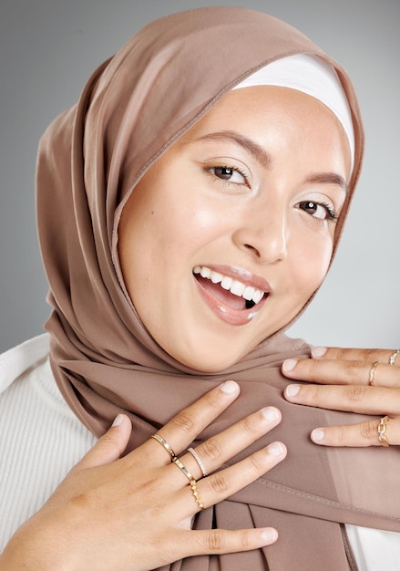 Ritratto in studio di bella e modesta donna musulmana isolata su uno sfondo grigio Giovane donna che indossa un hijab o un velo che mostra la tradizionale modestia araba mentre sorride e guarda la fotocamera