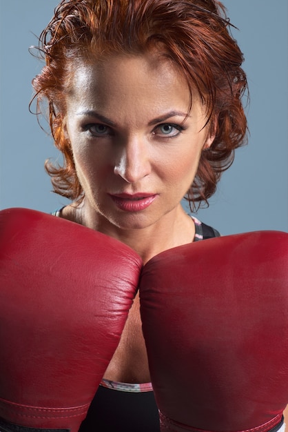 Ritratto in studio di donna matura sportiva in guantoni da boxe su grigio