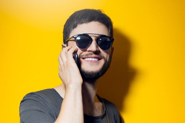 Ritratto in studio di giovane uomo sorridente utilizza lo smartphone