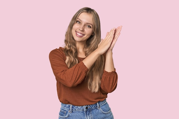 Ritratto in studio di una donna bionda caucasica che si sente energica e a suo agio sfregando le mani