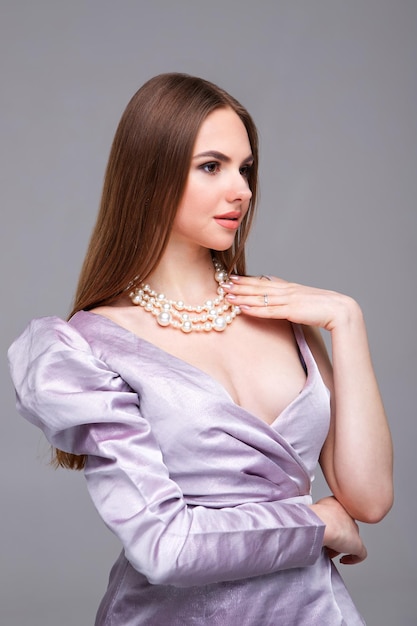 Ritratto in studio di una giovane ragazza con una collana di perle su uno sfondo grigio posto per la pubblicità Ritratto di profilo elegante di una bellissima modella