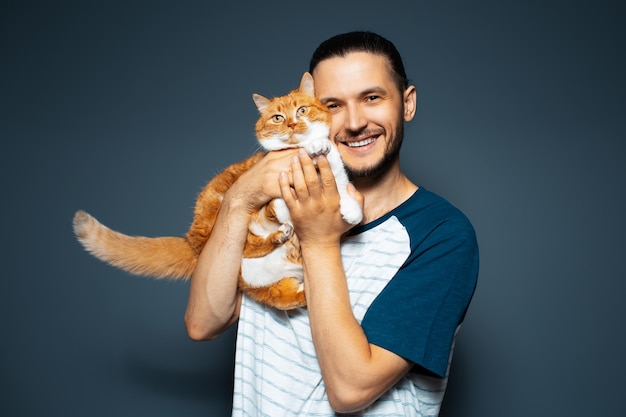 Ritratto in studio di uomo felice e gatto redwhite su sfondo blu