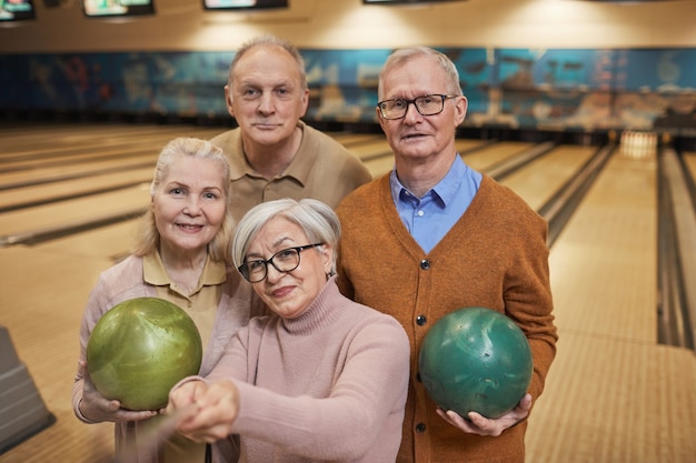 Ritratto in vita di un gruppo di persone anziane che scattano foto selfie mentre giocano a bowling e si godono l'intrattenimento attivo al bowling