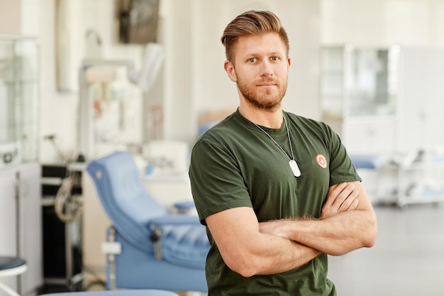 Ritratto in vita di un orgoglioso donatore di sangue in piedi nel centro di donazione medica con adesivo salva vita su che