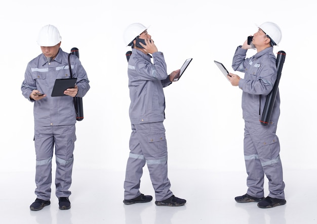 Ritratto integrale anni '50 anni '60 Uomo anziano asiatico in elmetto protettivo uniforme grigio come ingegnere elettrico, isolato. Il tecnico elettrico maschio porta la nota della lista di controllo del grafico della tavoletta digitale, studio di sfondo bianco