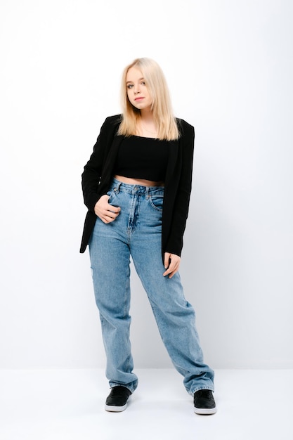 Ritratto integrale della ragazza dell'adolescente in jeans larghi e giacca nera