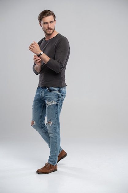 Ritratto integrale dello studio del giovane casuale in jeans e sorridere della camicia. Isolato su sfondo bianco.