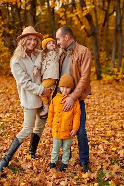 Ritratto integrale di bella famiglia con bambini nella foresta di sole autunnale