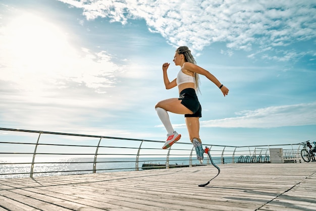 Ritratto integrale di una giovane sportiva disabile sicura di sé che corre veloce su un ponte